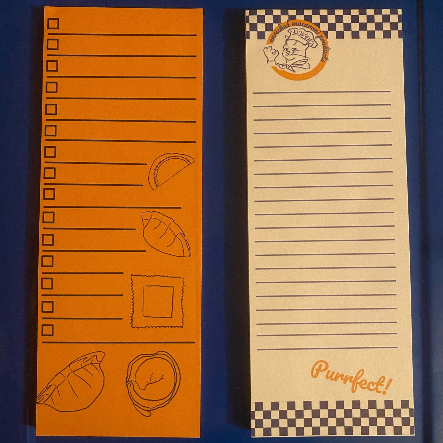 Two list note pads next two each other, the left one is yellow with a pasta design and checkboxes, the right has a blue and white checkered design with the Enriched Macaroni Products logo at the top